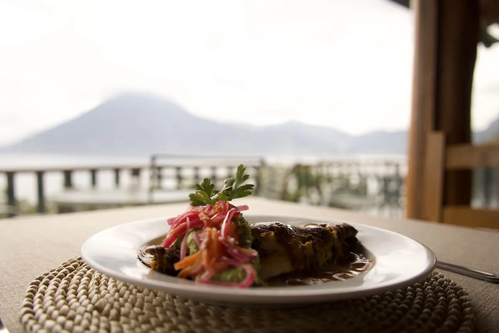 Plated meal at Loma de Atitlan restaurant with volcano and lake view in the background