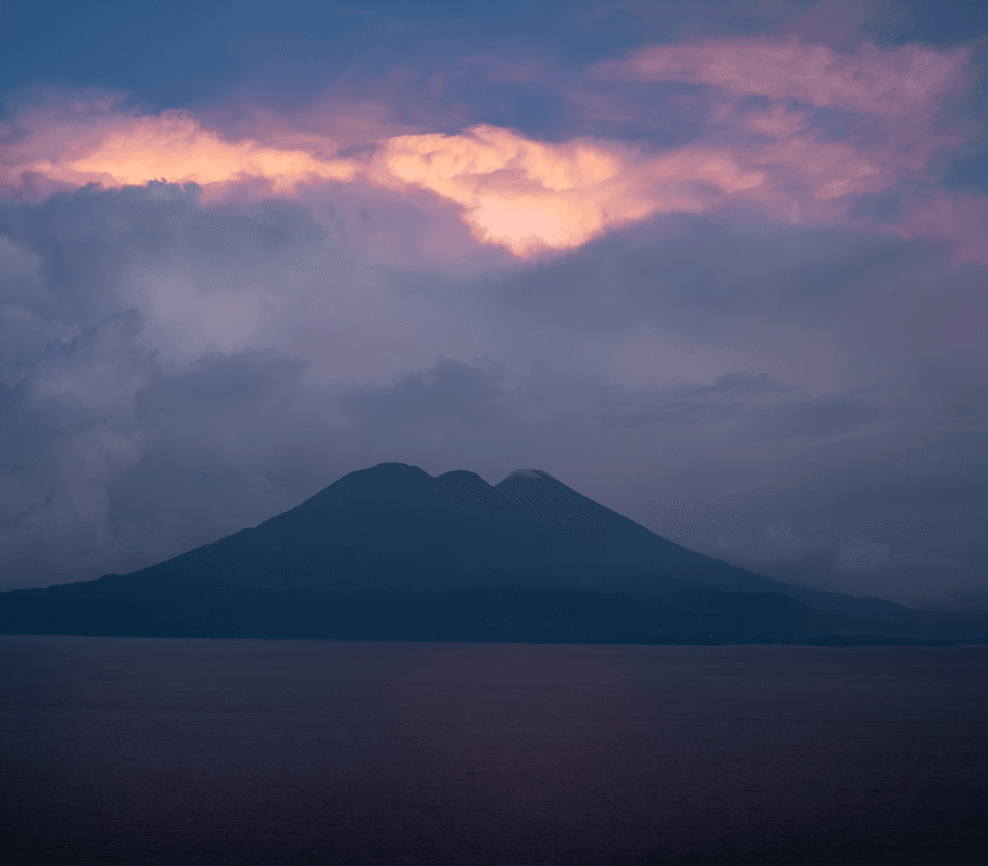 Volcano silhouette at dusk with purple sky over Lake Atitlan